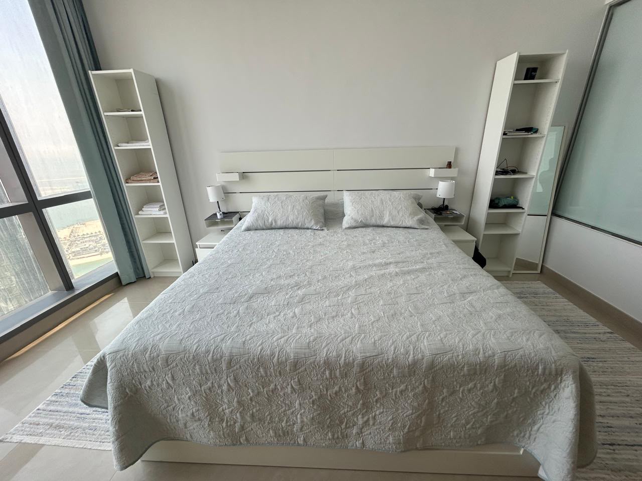 Modern white used bed with mattress and matching side tables available for sale in Abu Dhabi.